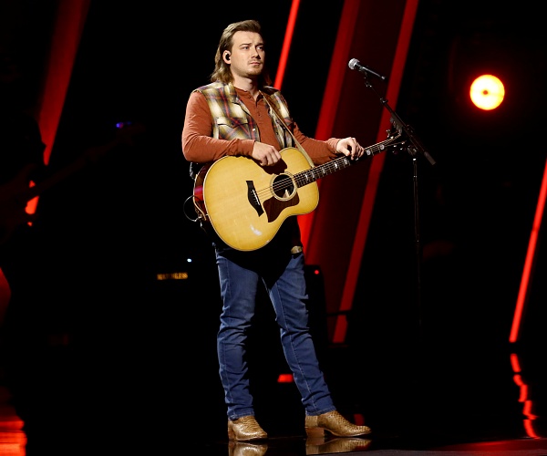 morgan wallen stands onstage holding guitar