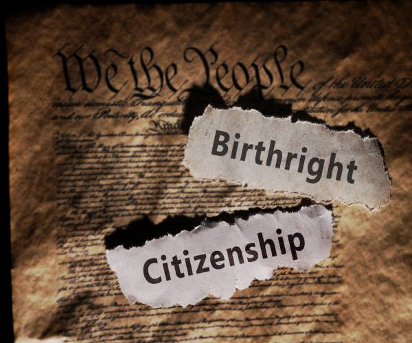 the words birthright citizenship on torn paper lying on a copy of the constitution