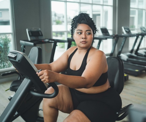 overweight woman riding exercise bike at gym