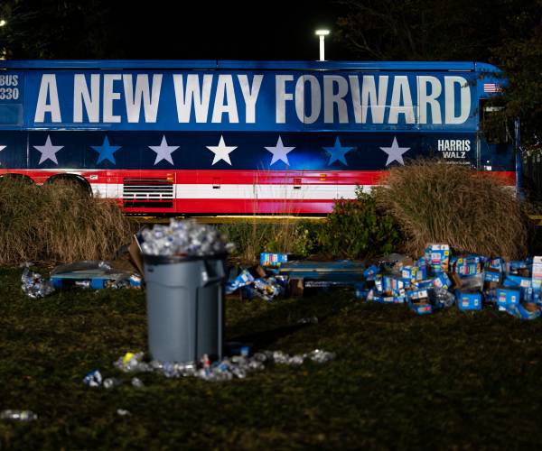 a harris-walz bus and trash on the ground after an election night party