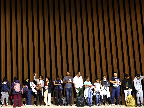 migrants against a border wall