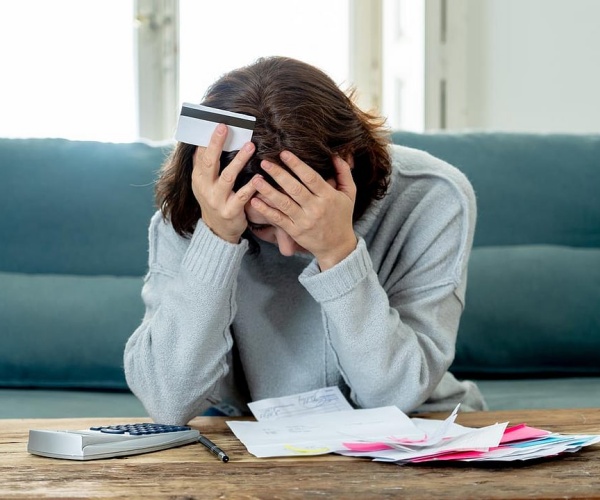 woman at table trying to figure out her medical bills with her head in her hands