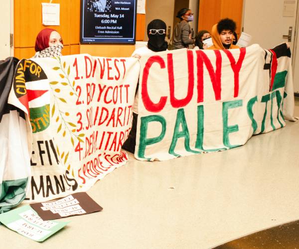 people crouch behind protest banners 