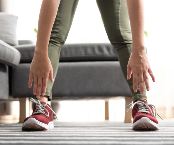 woman stretching to touch sneakers