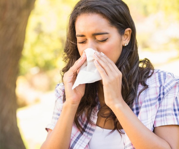 woman blowing her nose outside