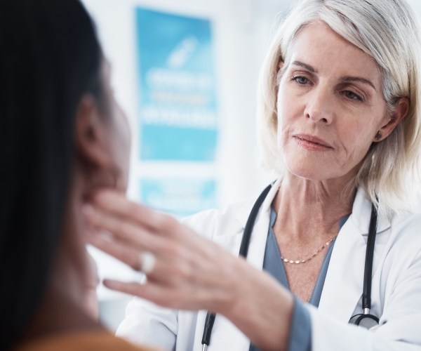 a doctor checking a patient's thyroid