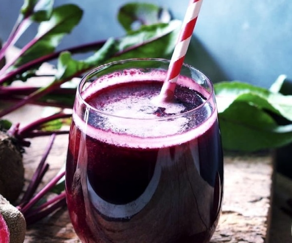 elderberry juice in a wine glass with a straw