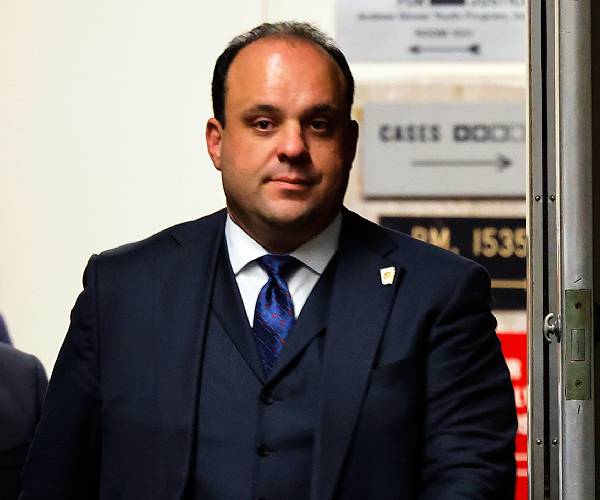 a man in a three piece suit entering a room through a doorway