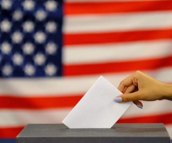 American flag, person putting ballot in box