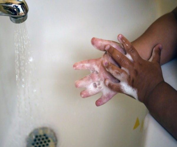 young boy washing hands in sink