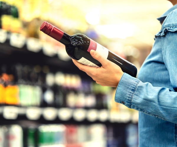 woman holding a bottle of wine and reading label