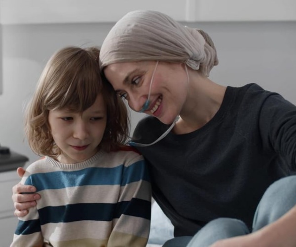 woman with a scarf on head and oxygen in nose sitting with her child