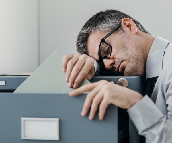 man at work dozing on filing cabinet