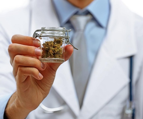 doctor holding up a glass container of cannabis