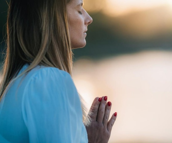 woman with hands together, eyes closed, meditating