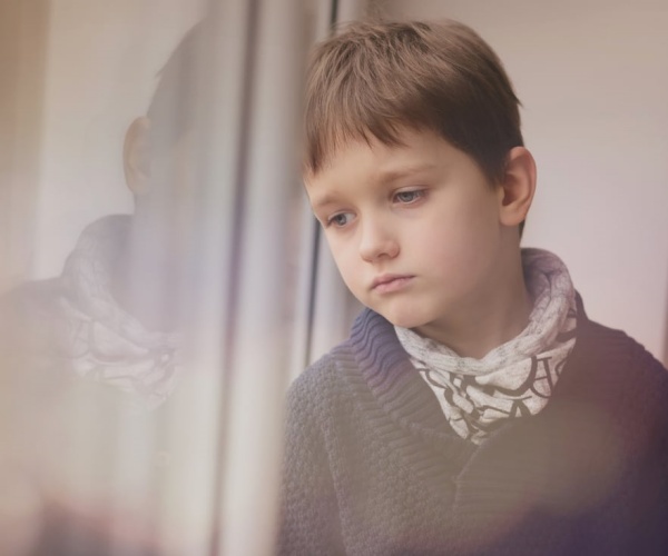 young boy with autism looking anxiously out window