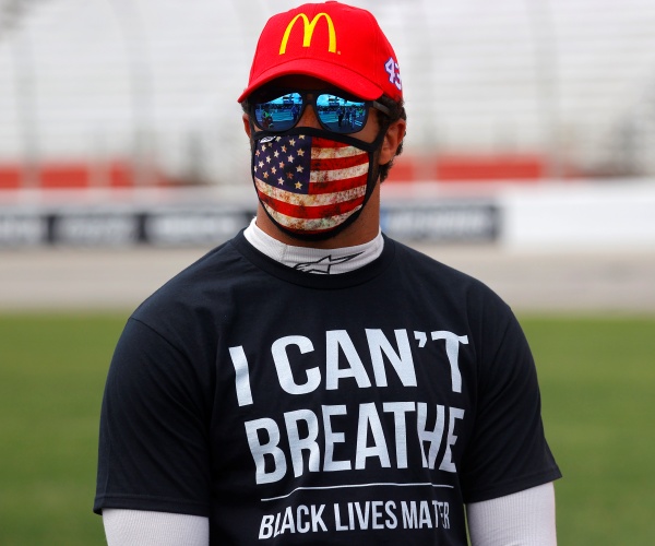 wallace in a black t shirt with "i can't breathe" on it with an american flag mask and mcdonalds baseball cap