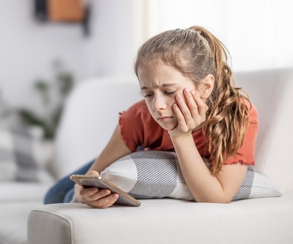 young girl looking said while scrolling on smartphone