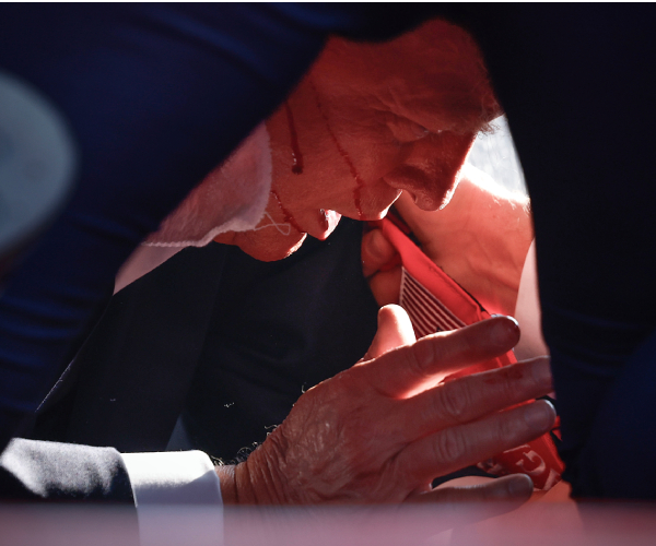 trump on the floor with his hand in front of him and blood on his face