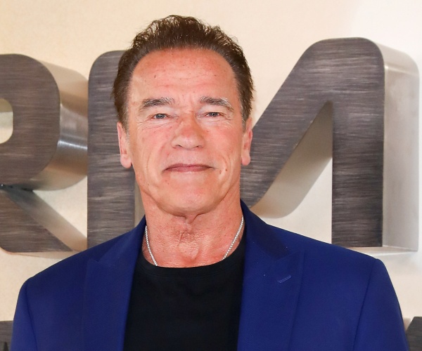 arnold schwarzenegger stands on red carpet