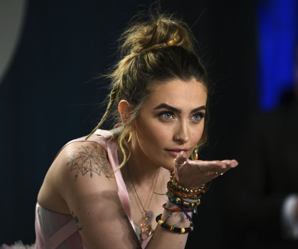 paris jackson is shown wearing an armful of bracelets and a spider web tattoo on her right arm