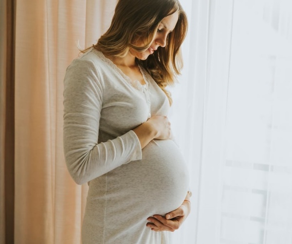 pregnant woman holding, looking down at stomach