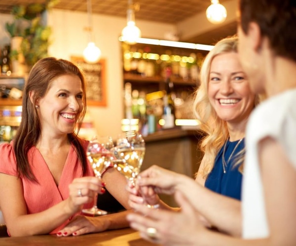 women drinking wine, cheering with their glasses