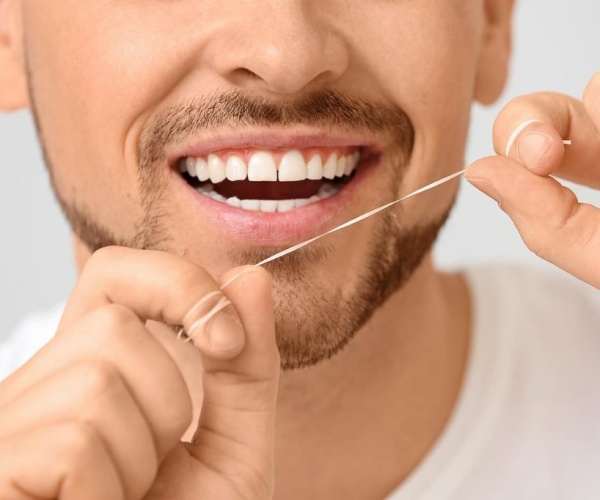 man smiling, flossing teeth