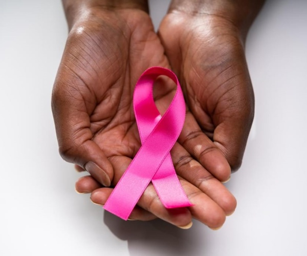 cupped hands holding a pink ribbon