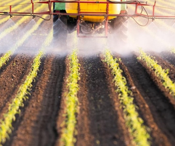 farmer spreading pesticides in field