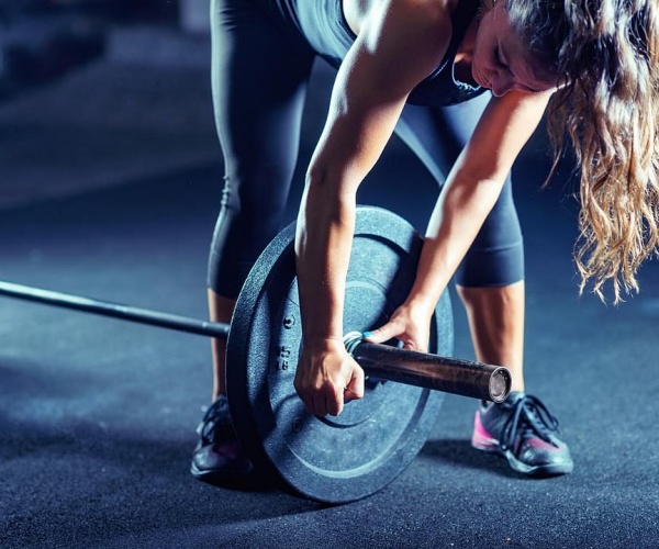 woman adding a weight while weightlifting in gym