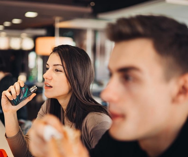 young adults at a bar, woman vaping