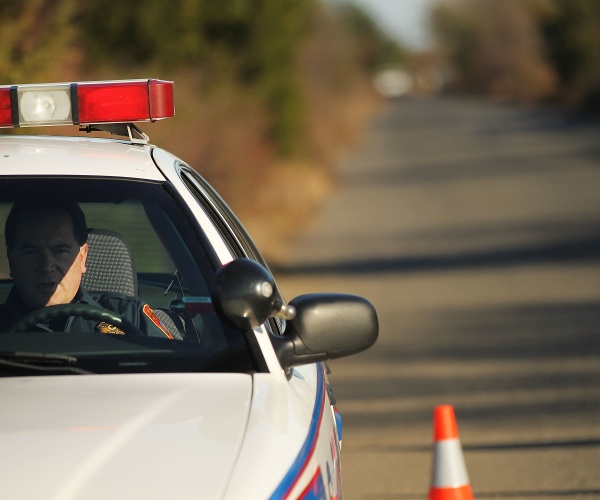 a police officer sits at the entrance of a road