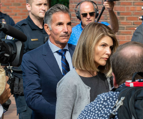 actress Lori Loughlin and husband Mossimo Giannulli exit a court house surrounded by reporters and media cameras