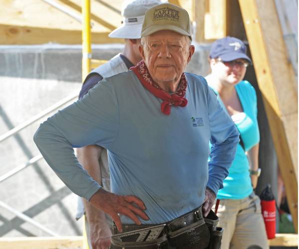 jimmy carter stands with his hands on his hips at a house building site