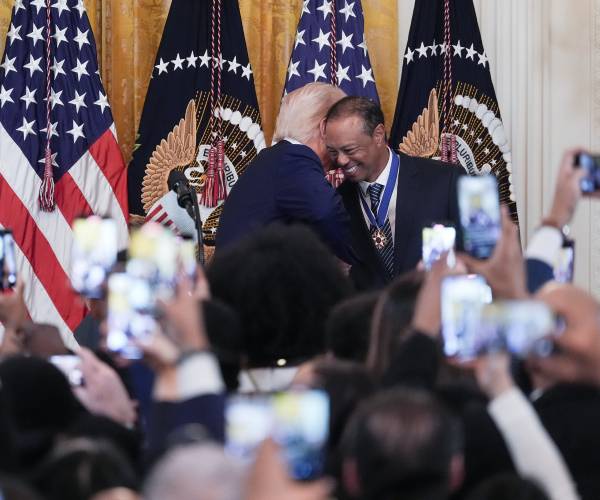 donald trump leans into tiger woods as people watch and record them with their phones