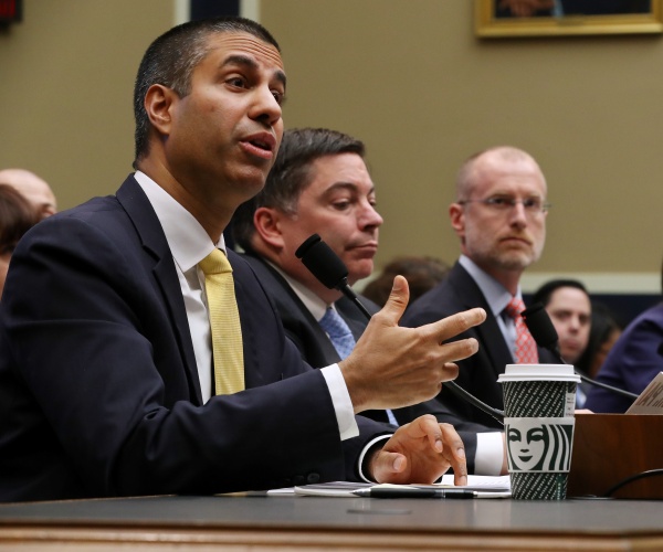 members of the fcc speak at a hearing with ajit pai speaking into the mic