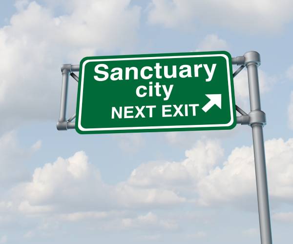 a highway sign that reads sanctuary city ahead