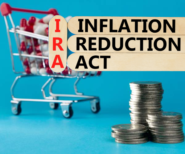 the words inflation reduction act written on tongue depressors with a shopping cart filled with pills and stack of coins