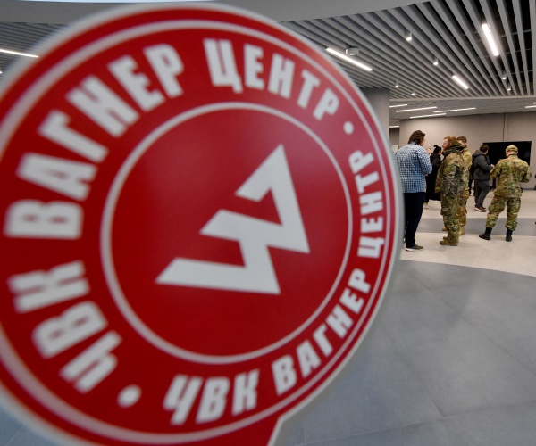 visitors wearing military camouflage stand at the entrance of the 'pmc wagner centre'