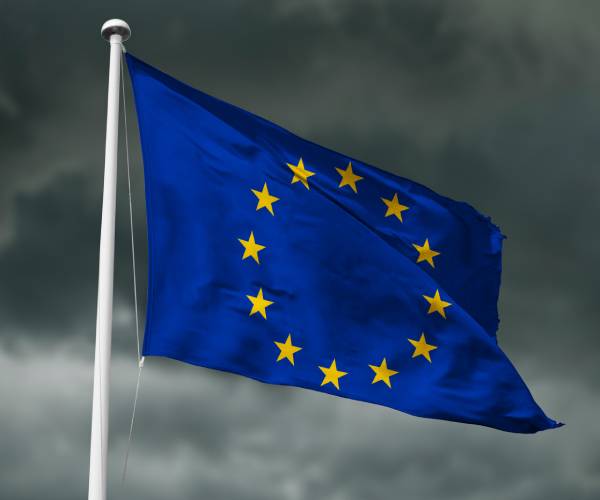 the flag of the european union flying in front of storm clouds