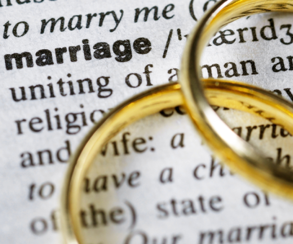 two wedding rings next to the word marriage on a dictionary
