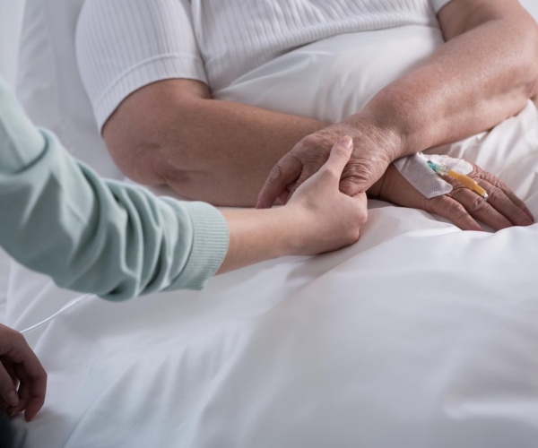 nurse with hands on patient in hospital bed