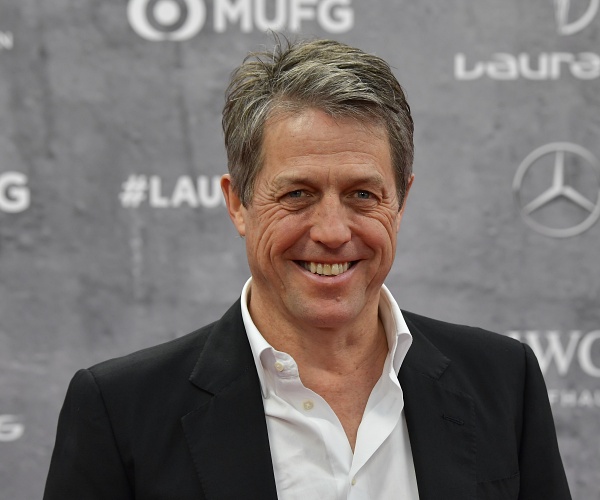 hugh grant stands on red carpet