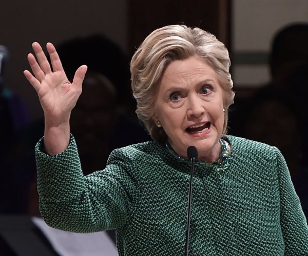 hillary clinton gestures while speaking into a microphone