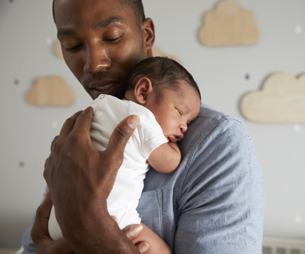 man holding sleeping baby on his shoulder