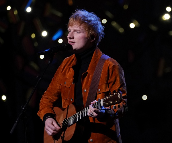 ed sheeran plays guitar and sings into mic onstage