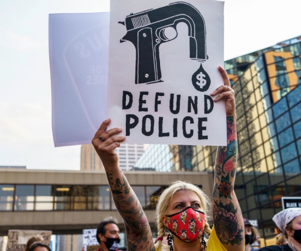 protester holds sign saying defund the police