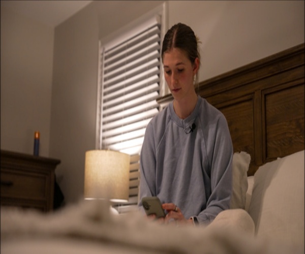 woman sitting in bed looking at sleep app on her phone