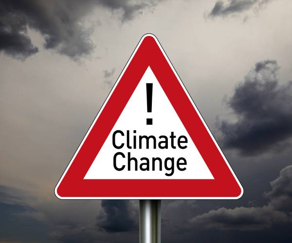 a street sign reading climate change in front of a dark cloudy sky